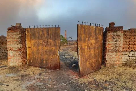 The old outer wall and broken iron gate of an abandoned factory Foto stock