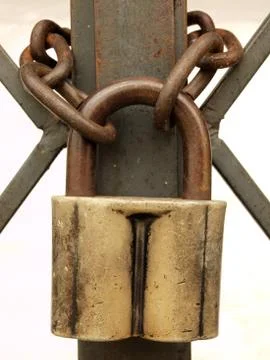 The old padlock and rusty chain on a metal lattice. Stock Photos