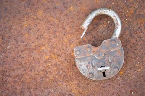 An old padlock with a key on a rusty sheet of metal, close-up, selective focu Stock Photos