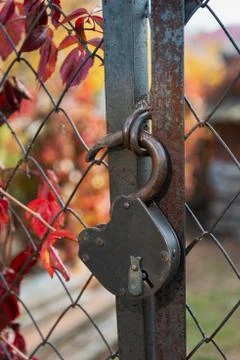 Old padlock on a rusty wire mesh gate Stock Photos