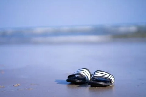 An old pair of flip-flops laying on an empty beach Stock Photos