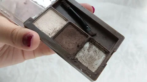 An old palette with eye shadow, face contouring in a womans hand.Makeup artist Stock Footage 314305539