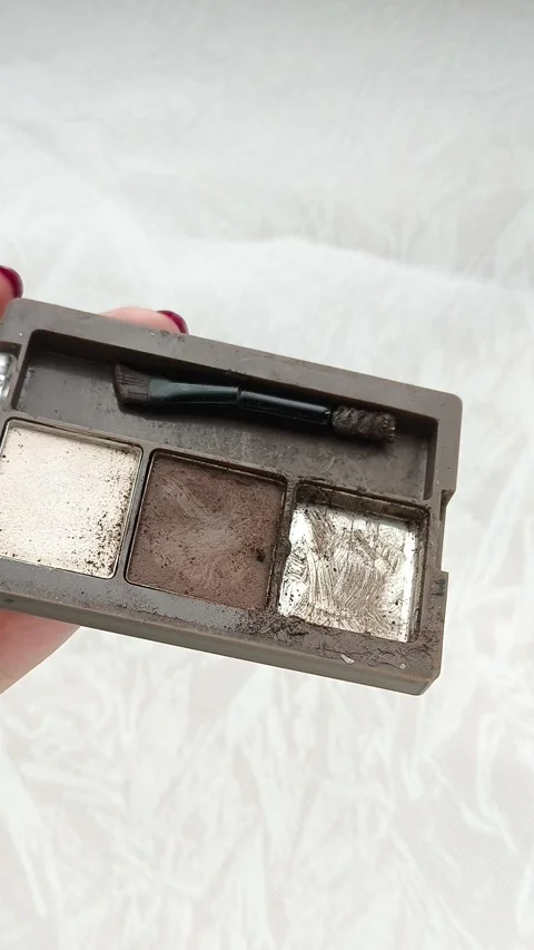 An old palette with eye shadow, face contouring in a womans hand.Makeup artist Stock Footage 314306599