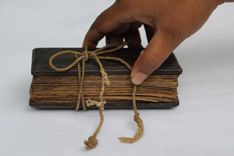 Old Palm leaf manuscripts bind together in a book and human hand holding it Stock Photos