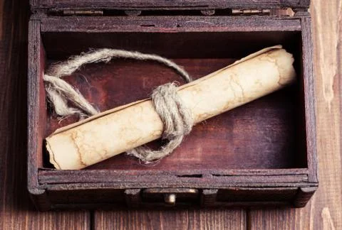 Old paper roll inside treasure chest on wooden background Stock Photos