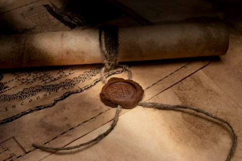 An old paper scroll sealed with a wax seal. The manuscript is rolled up and s Stock Photos