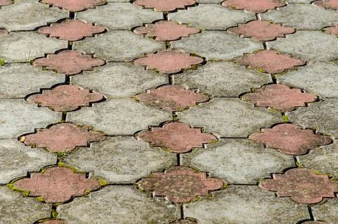 Old paving slabs. Grass makes its way through the cobblestone. Background Stock Photos