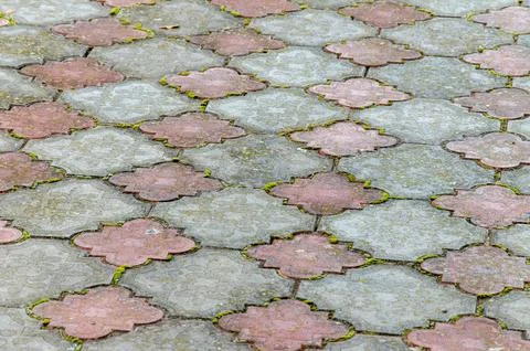 Old paving slabs. Grass makes its way through the cobblestone. Background Stock Photos