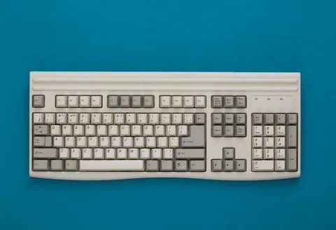 Old pc keyboard on blue background. Top view. Flat lay Stock Photos