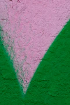 The old peeling wall is unevenly painted with pink and green spray paint Stock Photos