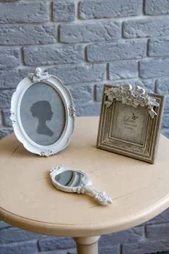 Old picture frames, lying mirror on the table with grey brick wall background Stock Photos