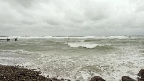 Old pier on the left and surfer on the right in the storm Stock Footage 82322546