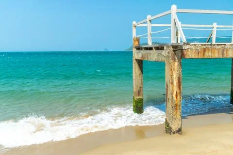 Old pier with railing over ocean with waves on beach Stock Photos