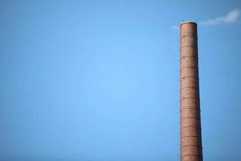 Old pipe made of bricks with the clouds imitating smoke Stock Photos