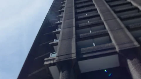 Old plane flying over Brutalist architecture in City Stock Footage 337279390
