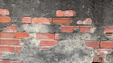 Old plaster falls from the wall and exposes the old red brick Stock Photos