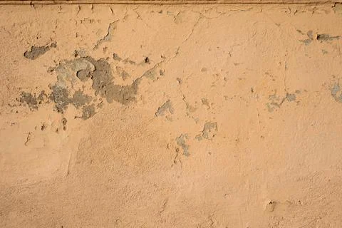 Old plastered texture light orange wall with scratches, cracks and chips. Stock Photos