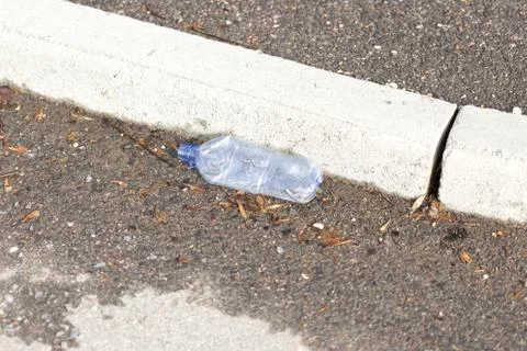 Old plastic bottle lying on the sidewalk Stock Photos