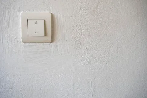 Old plastic switch with a bulb symbol on a white wall Stock Photos