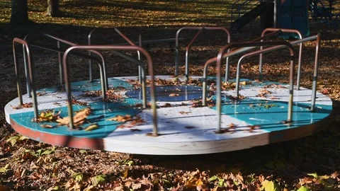 Old playground roundabout spinning on fall leaves with no people Stock Footage 280439659