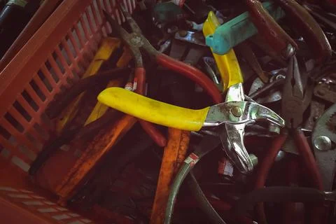 Old pliers in plastic basket. Second-hand tool for sale at tools market. Old  库存照片