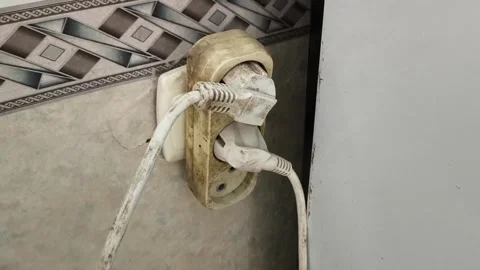 The old plugs are plugged into the socket with an adapter. dangerous connection Stock Footage 325288061