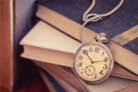 Old pocket watch on stack of books Stock Photos
