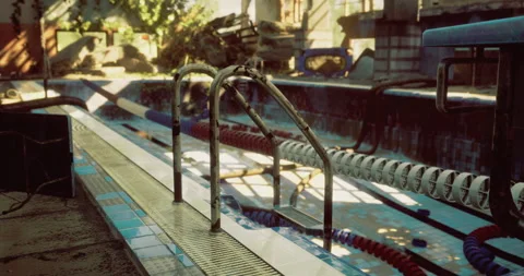Old pool with rusty railings and faded tiles in a deserted outdoor area Stock Footage 313433938