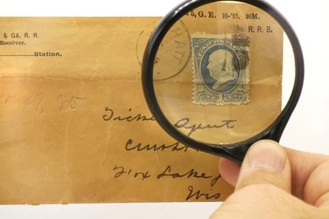 An old postage stamp honoring Benjamin Franklin under a magnifying glass. Stock Photos