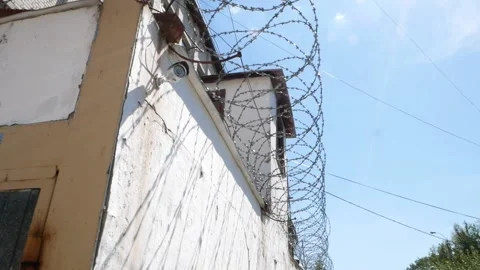 Old prison. Barbed wire. White wall with metal barbed fence. Stock Footage 140019610