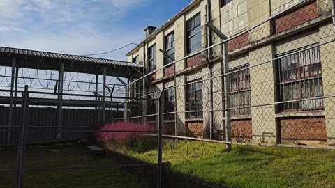Old Prison Yard Barbed Wire Fence and Jail Building on Sunny Day Stockbeeldmateriaal 255650228