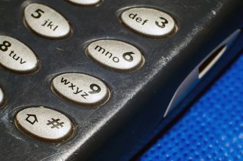 Old push-button cell phone on blue background Stock-Fotos