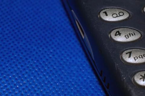 Old push-button cell phone on blue background Stock Photos