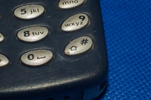 Old push-button cell phone on blue background Stock-Fotos