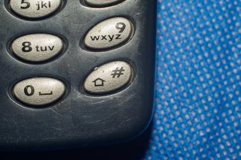 Old push-button cell phone on blue background Stock Photos