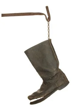 Old ragged rough leather boot on a rusty metal bracket Isolated on a white ba Stock Photos