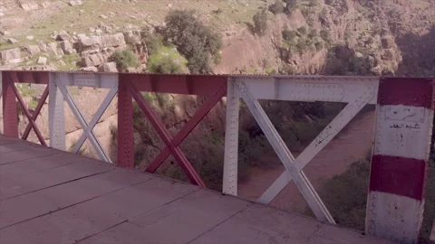 Old red and white iron truss bridge over rocky canyon in Morocco Stock Footage 334694442