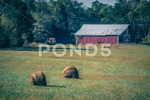 Old red barn and rotobales on farm landscape in the south Stock Photos