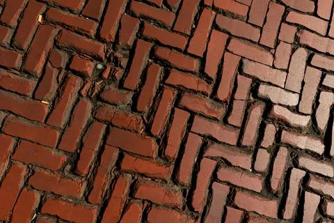 Old red brick paver texture in herringbone pattern weathered pavement background Stock Photos