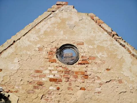 Old red brick structure featuring peeling paint and small circular glass wi.. Stock-Fotos