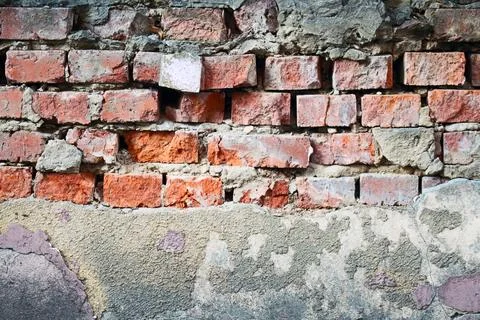 Old red brick wall with decaying cement and crumbling plaster texture Foto stock