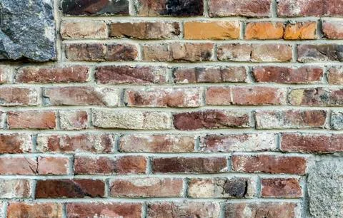 Old red brick wall with granite stones insertion, vintage worn masonry Stock-Fotos