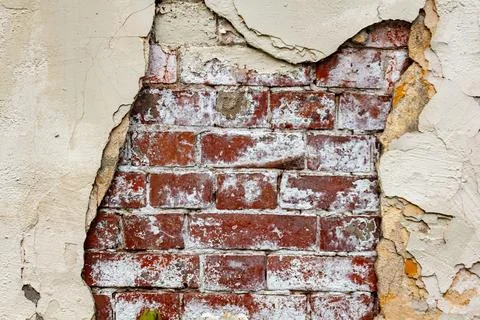 Old red brick wall hidden behind peeling white plaster in ruined building Stock Photos