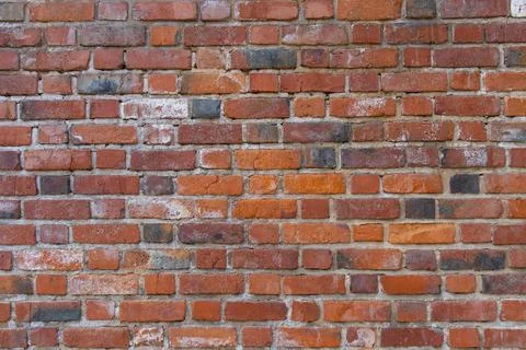 Old red brick wall texture with weathered surface and white stains. Stock Photos