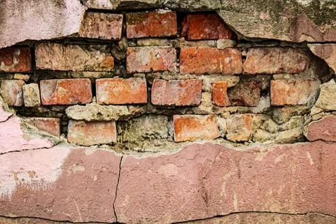 Old red brick wall through broken pink plaster surface with cracks and texture Stock Photos