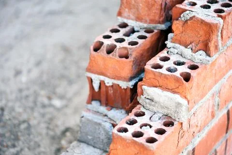 Old red building bricks forming a wall still undergoing construction with cem Stock Photos