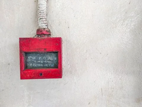 Old red fire alarm button on textured white wall Stock Photos