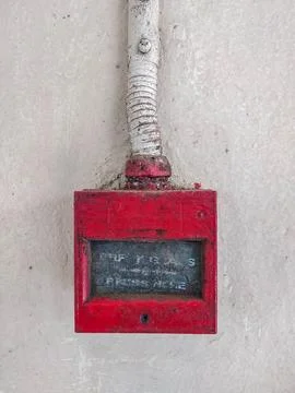 Old red fire alarm button on textured white wall Stock Photos