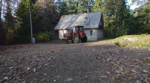 Old red tractor near to farmer house in forest Stock Photos