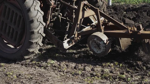 Old red tractor with plow plowing the land. The beginning of its agriculture. Stock Footage 129657522